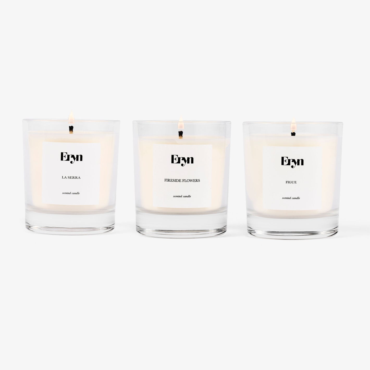 Image of three Eryn candles in a row on grey background including the scents LA SERRA, FIGUE AND FIRESIDE FLOWERS