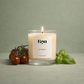La Serra luxury candle by Eryn in neutral setting with vine tomatoes and fresh basil next to it