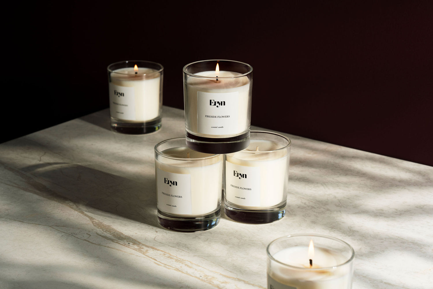 Image of clean burning scented candle Fireside Flowers by Eryn lit on burgundy and marble background